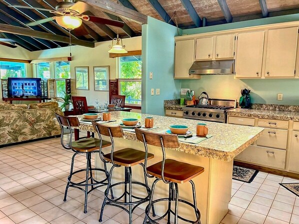A spacious kitchen with a large island, bar stools, and a dining area with a sofa.