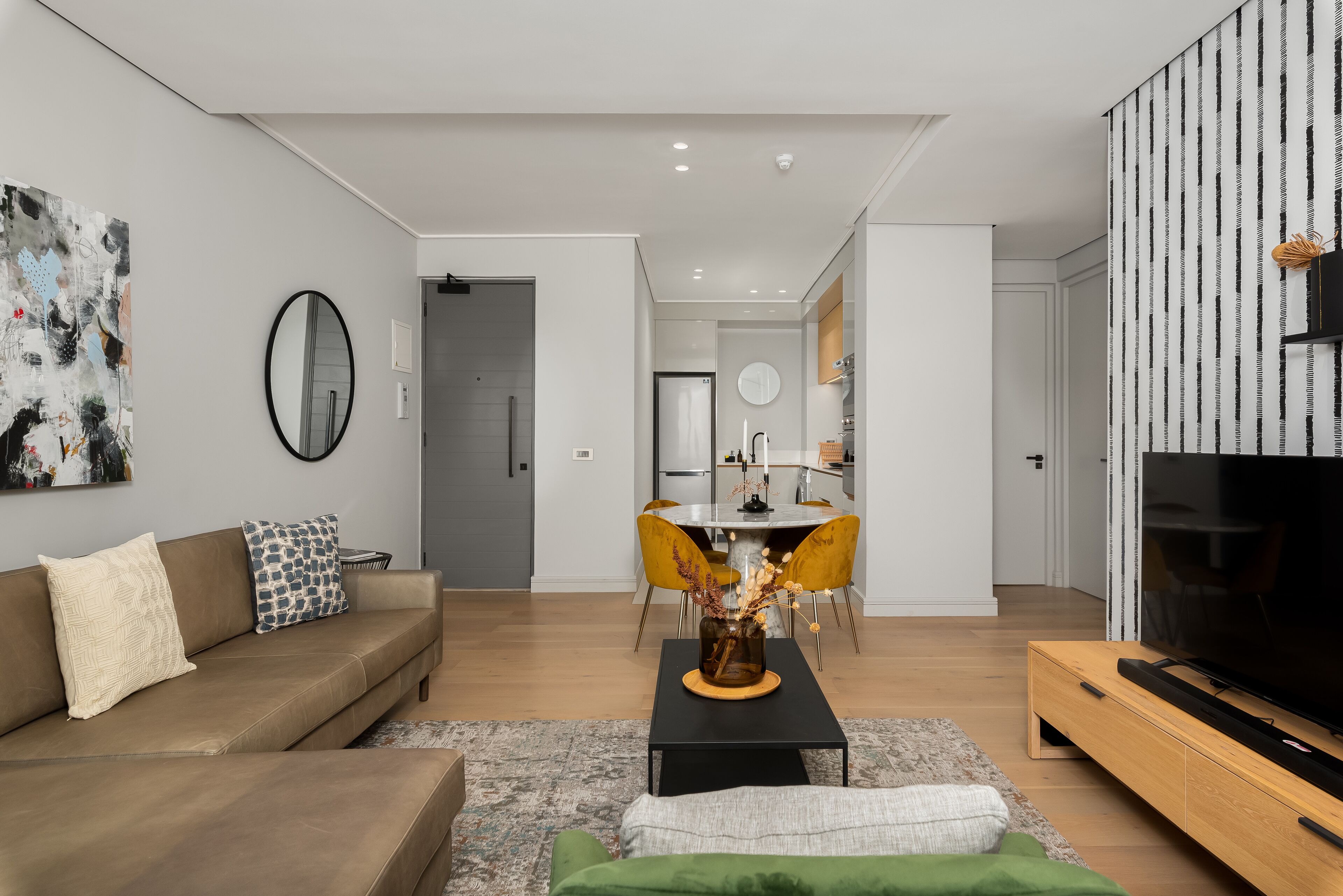 Una sala moderna con sofá, mesa de centro y televisor.  Hay un comedor con mesa y sillas.
