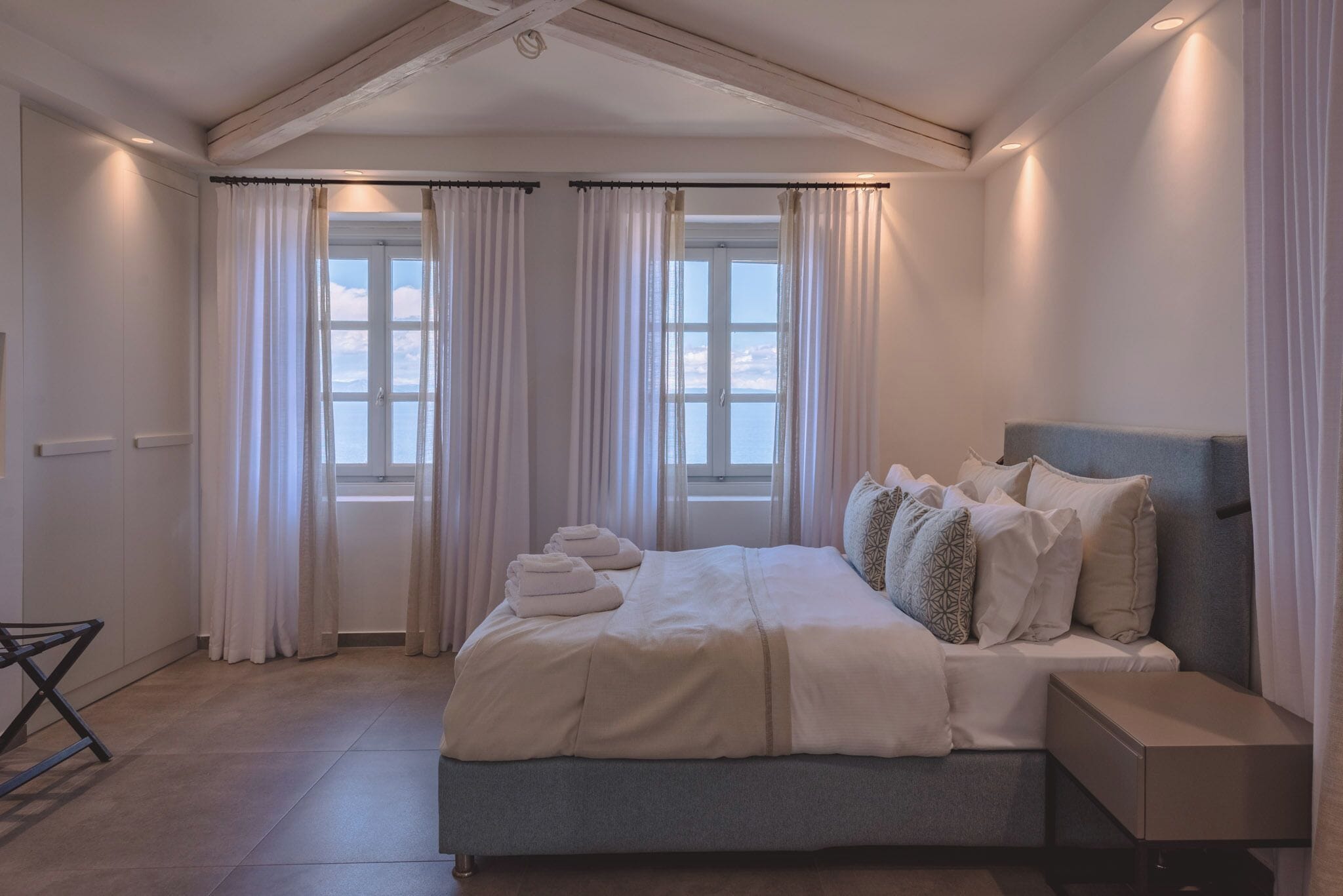 A bedroom with a bed, curtains, a window, and a bedside table.