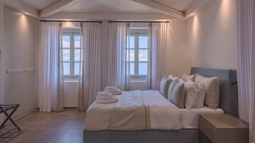 A bedroom with a bed, curtains, a window, and a bedside table.
