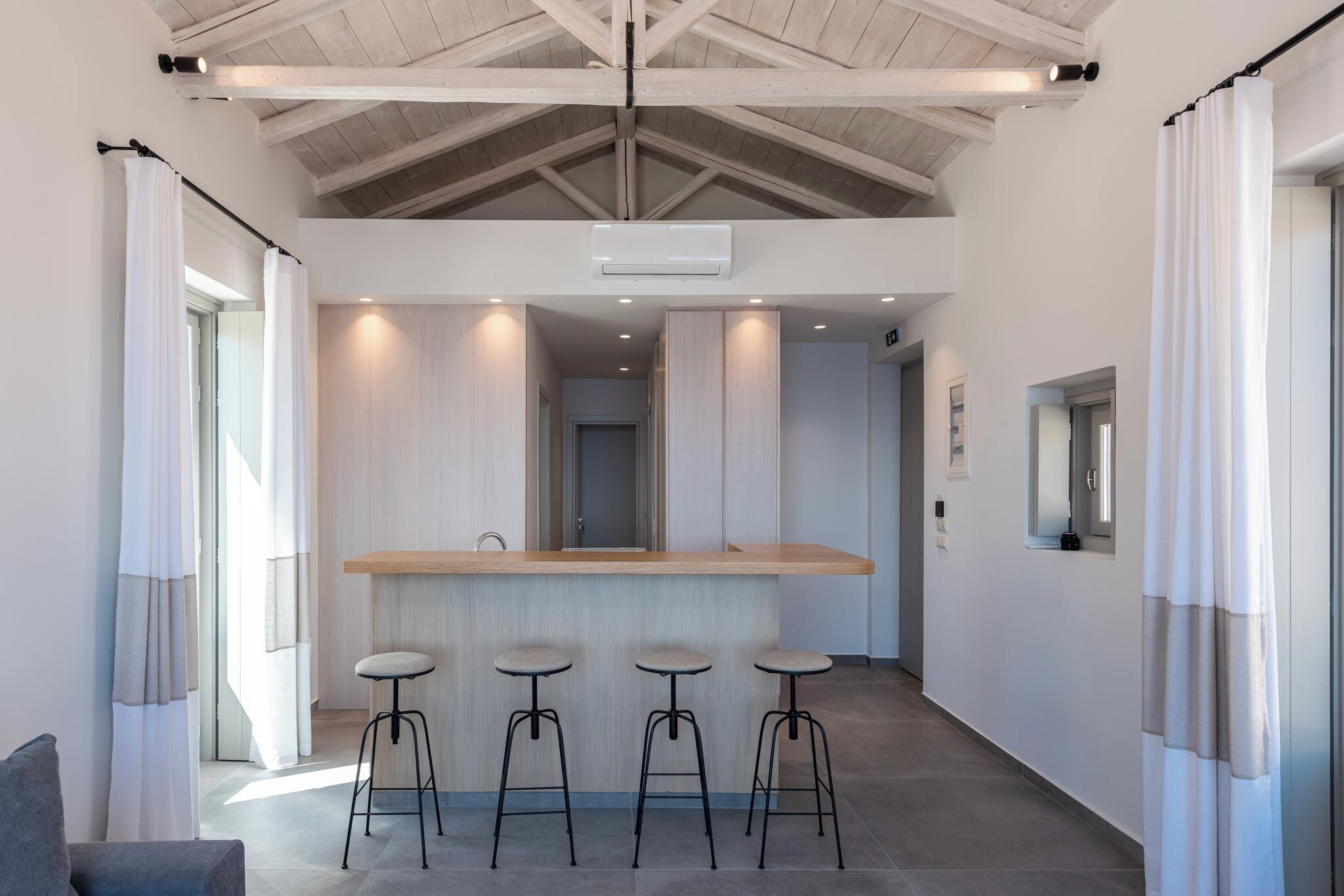 A modern kitchen with a central island, bar stools, and pendant lighting.