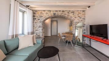 A modern living room with a stone archway, a sofa, a dining table, and a TV.