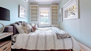 Relax in this serene bedroom with a large bed, shelving, and a flat-screen TV.