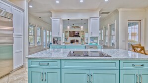 Une cuisine spacieuse avec des meubles de couleur turquoise, un plan de travail en granit et un îlot central.