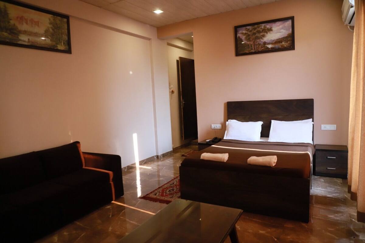 A hotel room with a bed, a sofa, a small table, and a carpet.