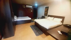 A hotel room with two beds, a desk, a chair, a phone, and an air conditioning unit. - Rio Forest Resort (Karjat)