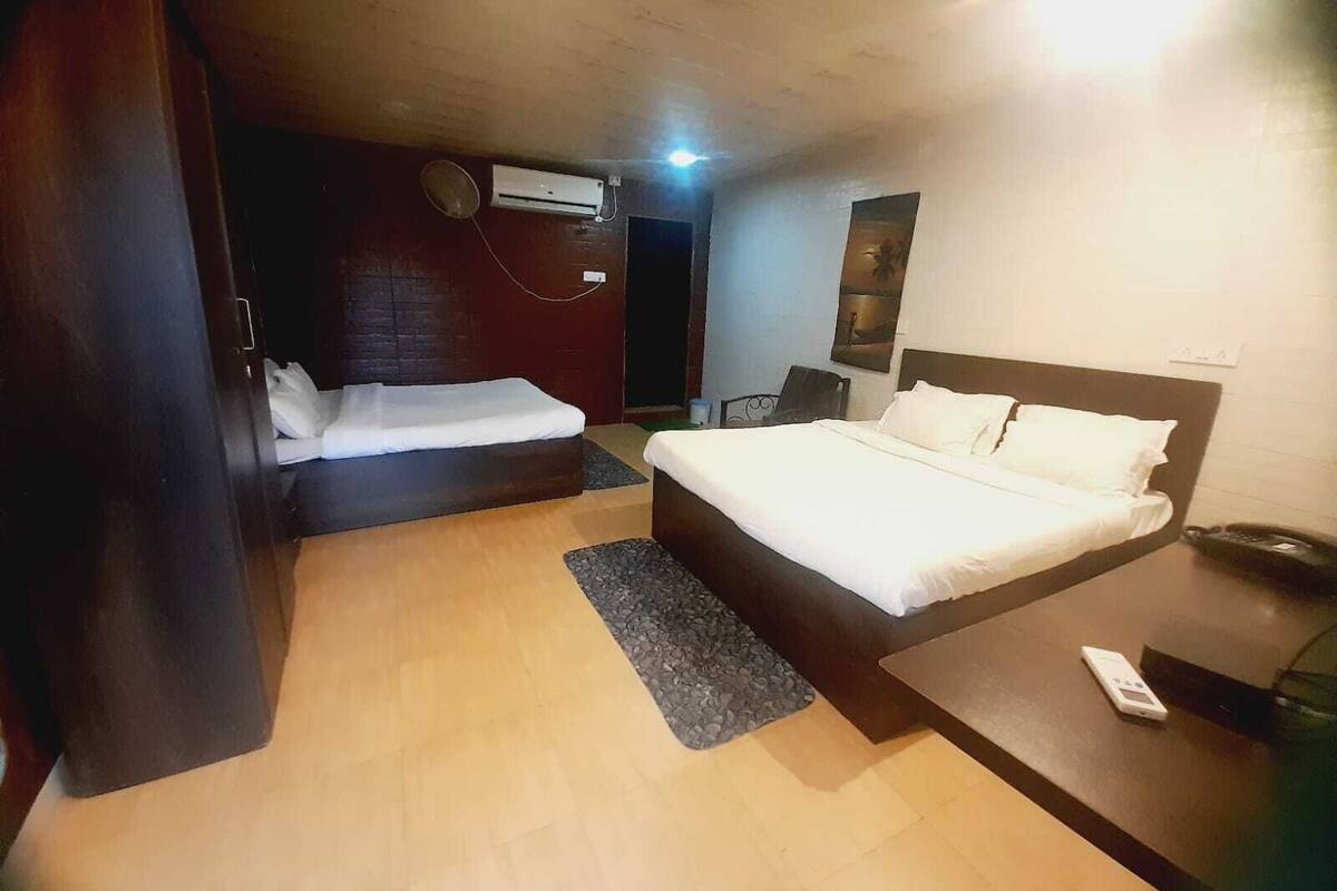 A hotel room with two beds, a desk, a chair, a phone, and an air conditioning unit.