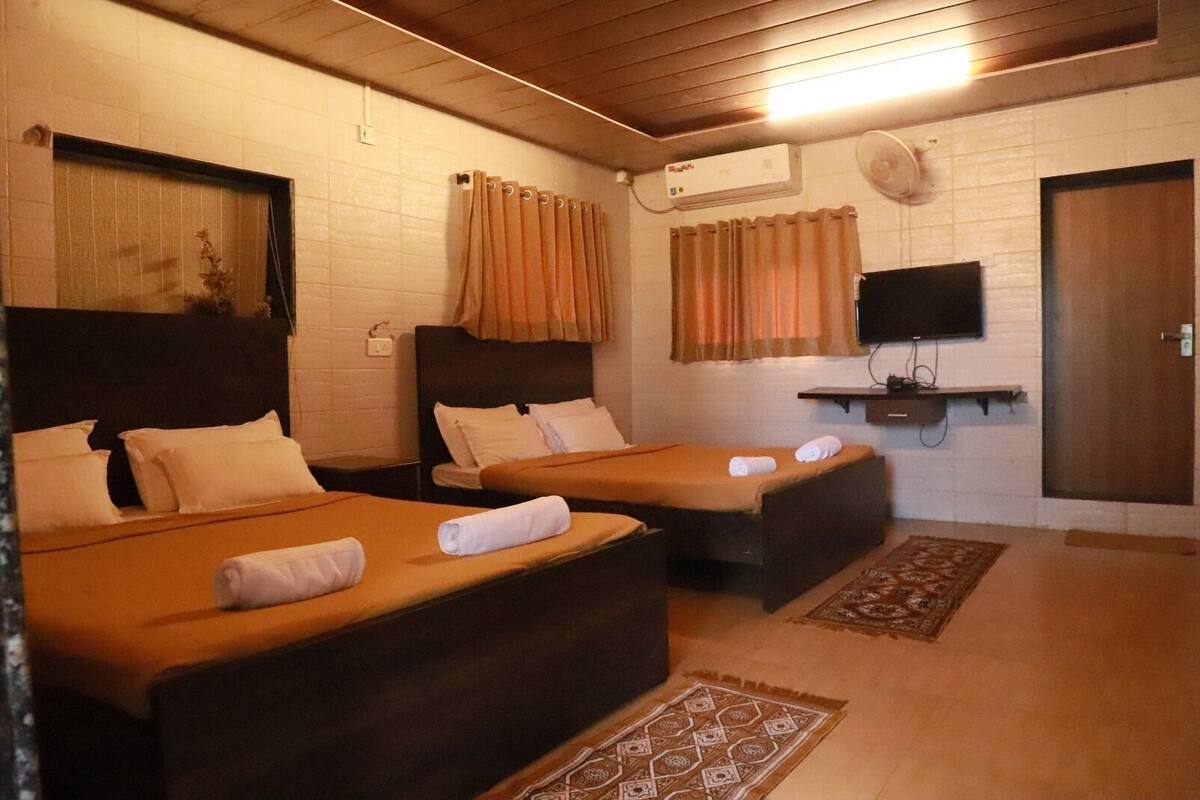 A hotel room with two beds, a TV, and a heater.