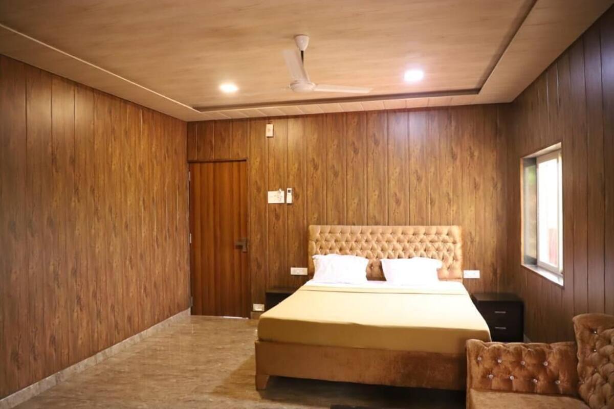 A bedroom with a large bed, wooden walls, a ceiling fan, and a window.