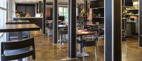 Un restaurante moderno con techos altos, detalles en madera oscura y una variedad de opciones de asientos, incluyendo mesas y sillas.