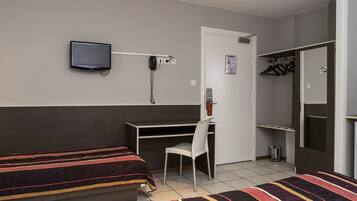 Een hotelkamer met twee bedden, een bureau, een stoel, een televisie, een telefoon en een kast.