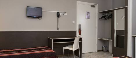 A hotel room with two beds, a desk, a chair, a TV, a phone, and a closet.