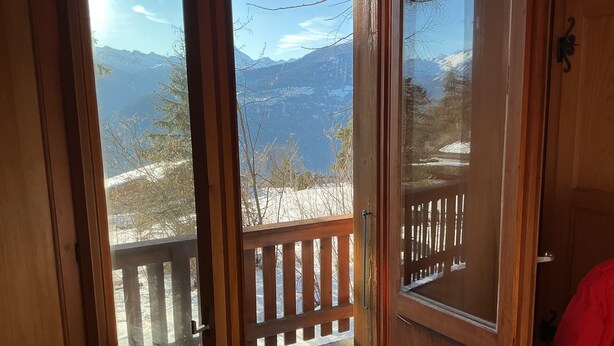 A wooden door with a view of a snowy mountain landscape through a glass window. - chalet with breathtaking views of the alps (Crans-Montana)