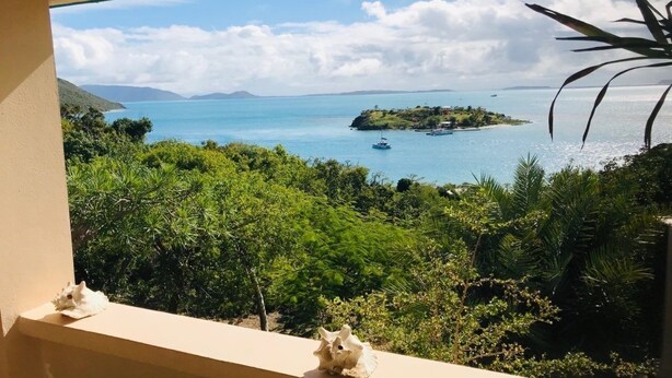 Un balcón con vistas a un paisaje costero, que incluye una pequeña isla y el mar.