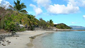Una playa con aguas cristalinas, palmeras y una orilla de arena.