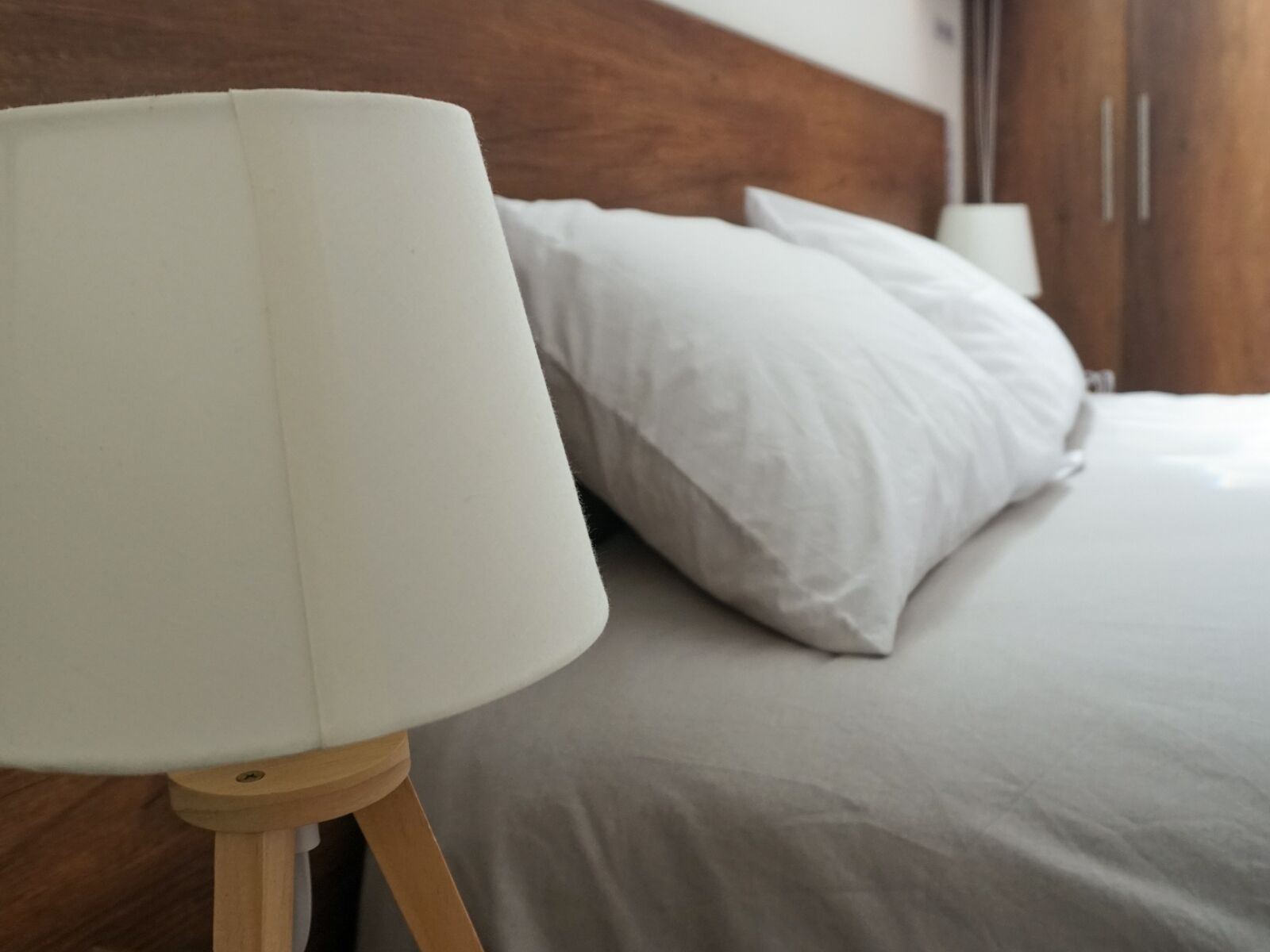 Un letto con biancheria bianca e una testiera in legno.