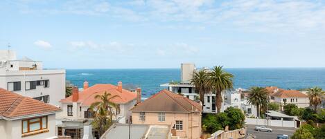 A coastal residential area with houses, a street, and a view of the ocean.