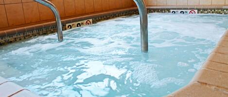 A hot tub with metal railings and a tiled wall.