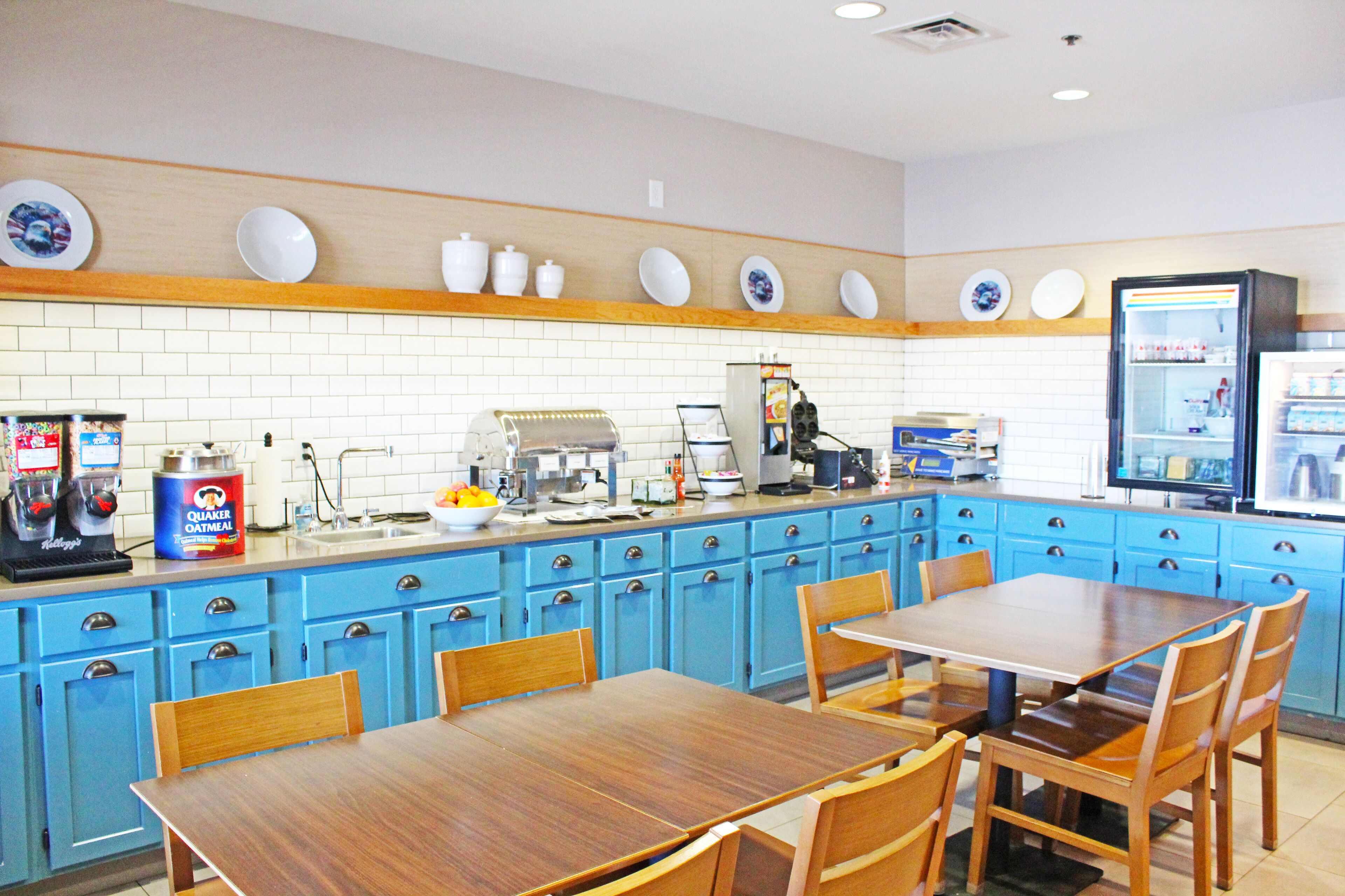 Une cuisine avec des meubles de rangement bleus, une machine à café et un réfrigérateur.