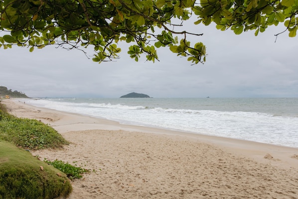 A beach with a sandy shore, waves, and a distant island. - La Bete Nautilus Ap Beto Carrero (Penha)