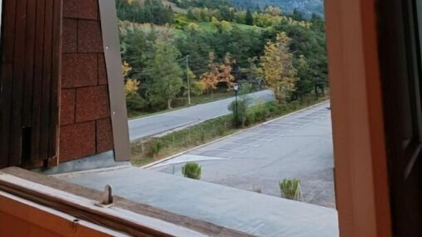 A window with a view of a mountain range and a road. - Grand Studio 3 Personnes Idéalement Placé (Barcelonnette)