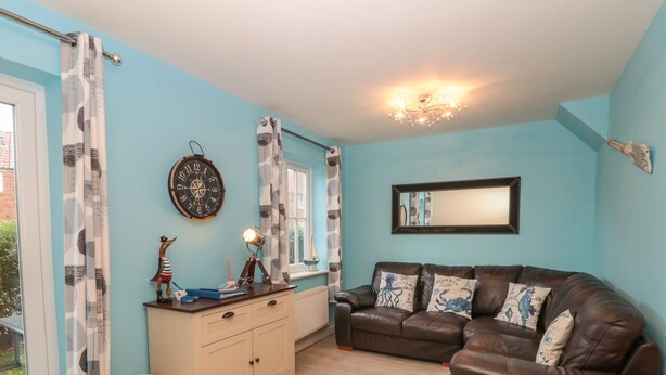 A living room with a brown leather sofa, a wooden cabinet, and a window with curtains.