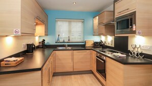A modern kitchen with wooden cabinets, a microwave, and a sink.