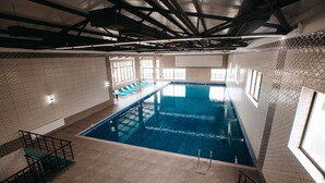 Una piscina interior con agua cristalina azul, paredes de azulejos y un diseño moderno.