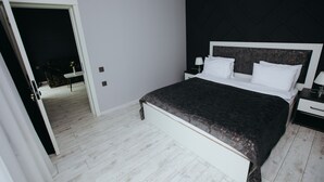 Un dormitorio con una cama grande, paredes blancas y un cabecero oscuro.