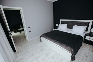 Un dormitorio con una cama grande, paredes blancas y un cabecero oscuro.