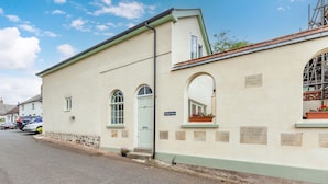 En byggnad med en ljusgrön fasad, en blå dörr och en skylt med texten ”Sunday Cottage”.