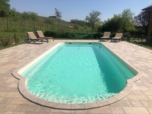 Una piscina al aire libre de temporada, sombrillas, tumbonas