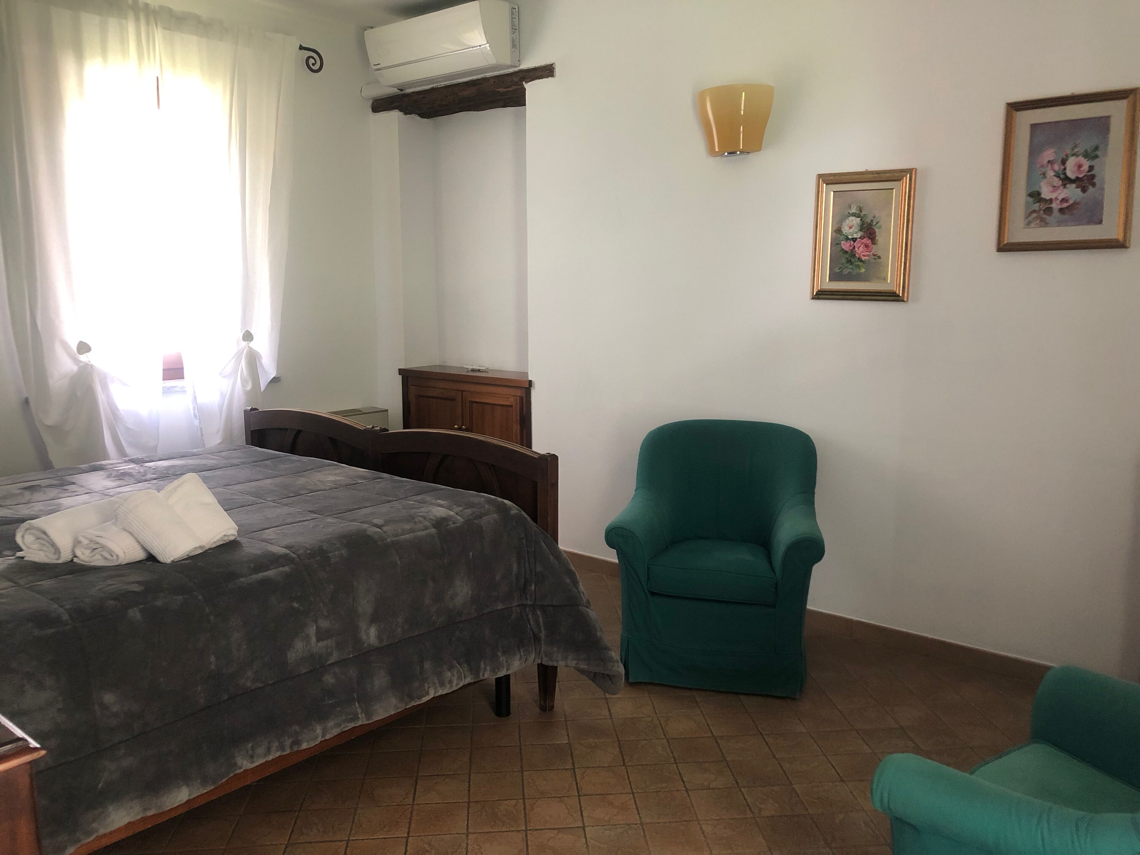 Een slaapkamer met een bed, een stoel, een kledingkast, een airconditioning en een wandlamp.