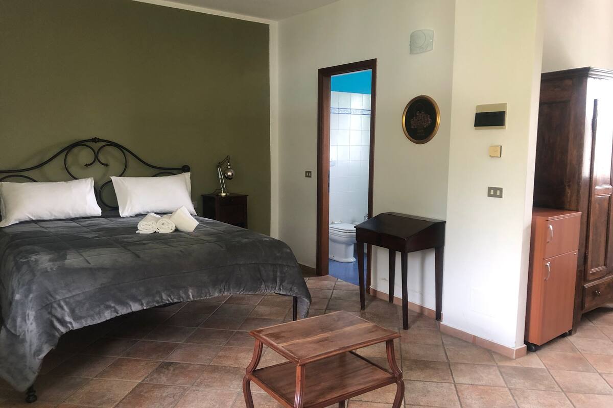 A bedroom with a bed, bedside table, and a small wooden stool.