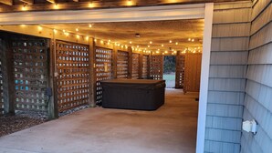 A covered outdoor area with a concrete floor, wooden beams, and string lights. - Goldie St Retreat - Heart of KDH, hot tub, pet friendly, centrally located  (Kill Devil Hills)