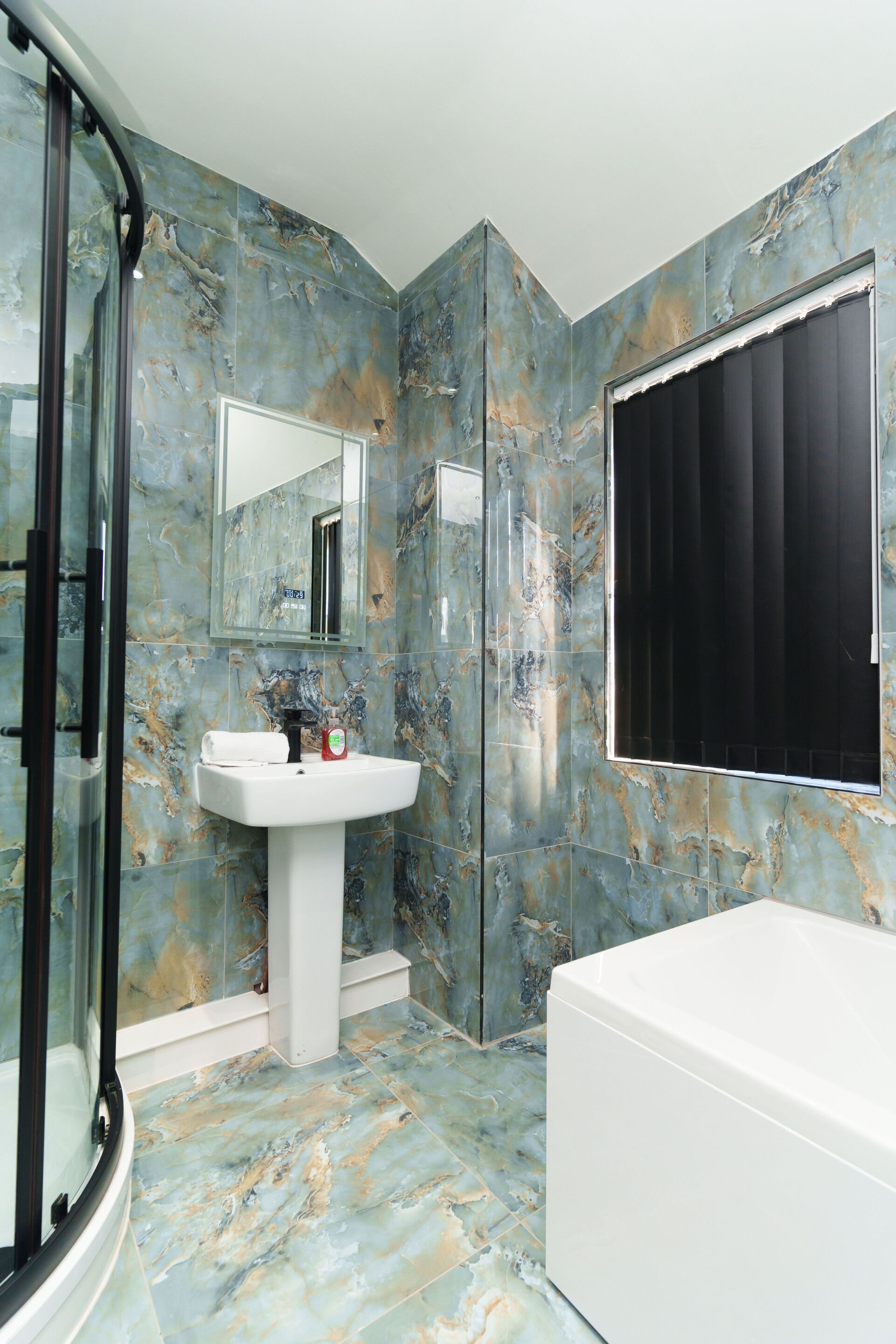 A bathroom with a glass shower enclosure, a sink with a mirror above it, and a bathtub.
