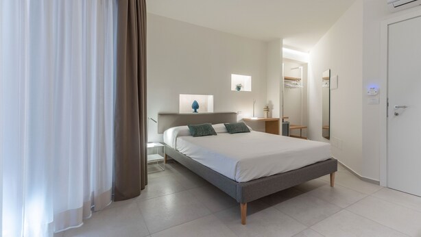Ein modernes Schlafzimmer mit Bett, Nachttisch, Spiegel und Kleiderschrank.