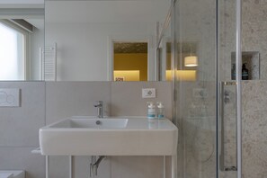 A modern bathroom with a white sink, a glass-enclosed shower, and a mirror above the sink.