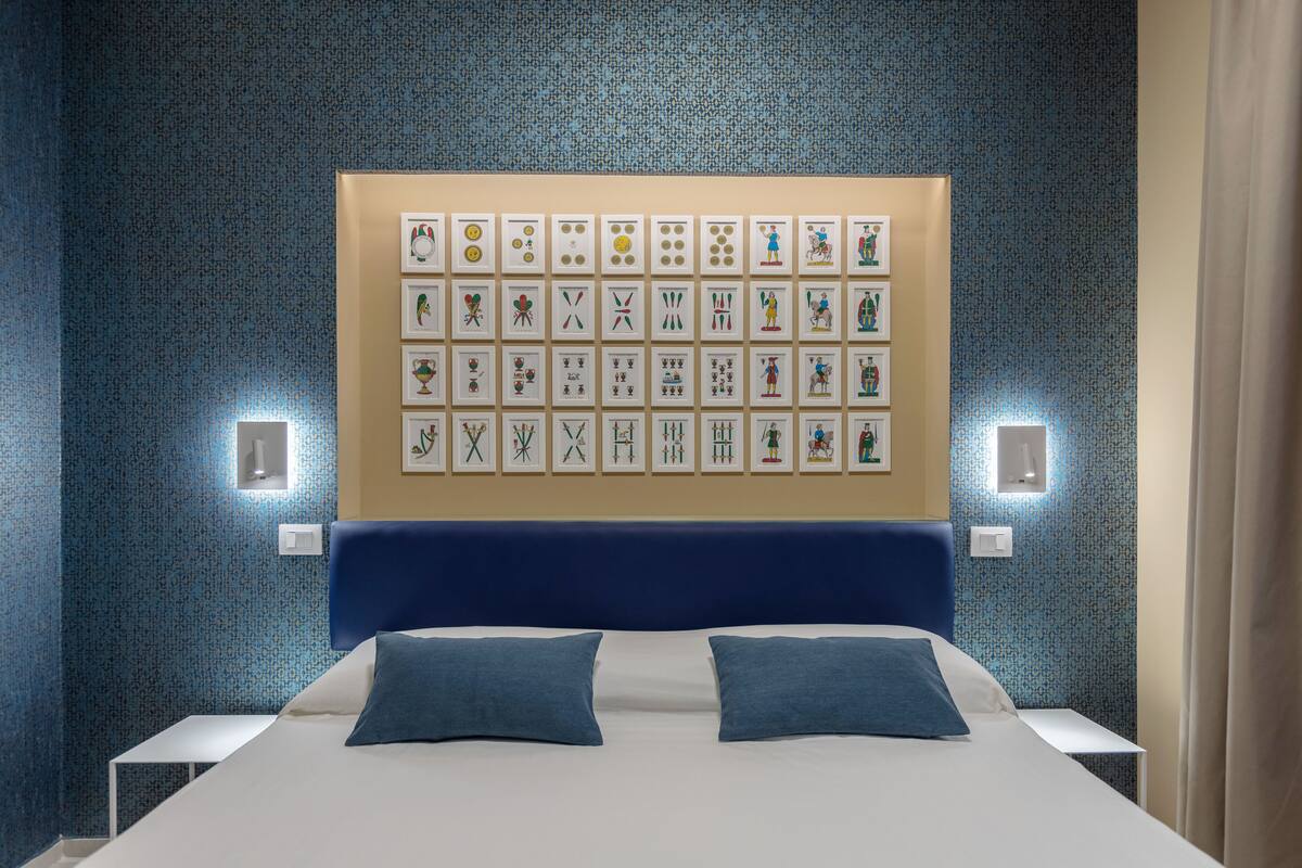A hotel room with a large bed, two pillows, a headboard, and a wall decorated with framed pictures.