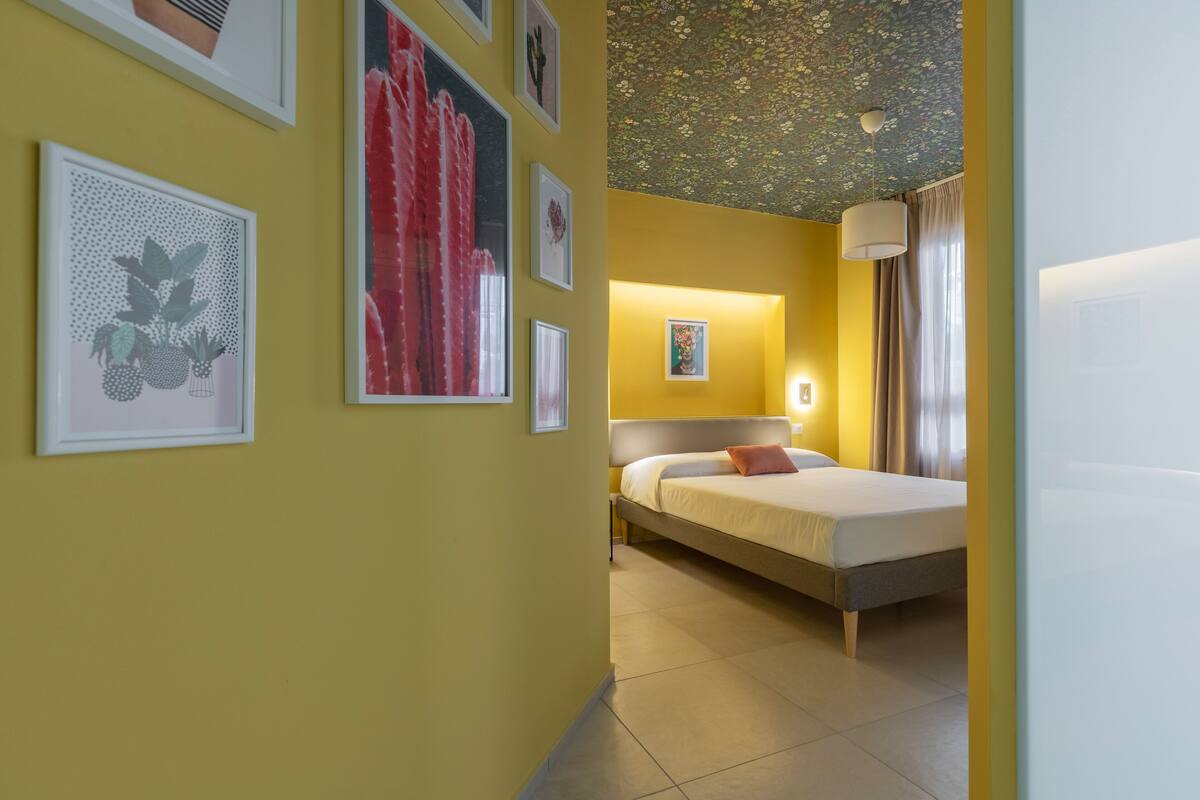 A hotel room with a bed, a nightstand, and a wall with framed artwork.