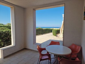 Quarto com vista para o mar, uma mesa redonda com cadeiras e piso de azulejos.