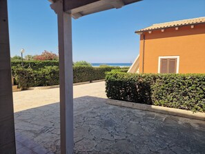 A paved pathway leading to a building with a view of the sea.