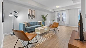 En moderne stue med blå sofa, to læderstole, sofabord og fjernsyn.