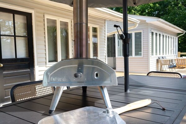 A portable grill on a deck with a house in the background.