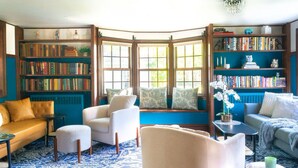A cozy reading nook with a bay window, bookshelves, and comfortable seating.