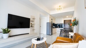 A modern living room with a flat-screen TV, a brown leather sofa, a small white coffee table, and a potted plant. - HAYA SOHO SAIGON (Ho Chi Minh City)