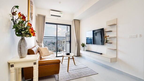 A modern living room with a sofa, a coffee table, a TV, and a large window with curtains. - HAYA SOHO SAIGON (Ho Chi Minh City)