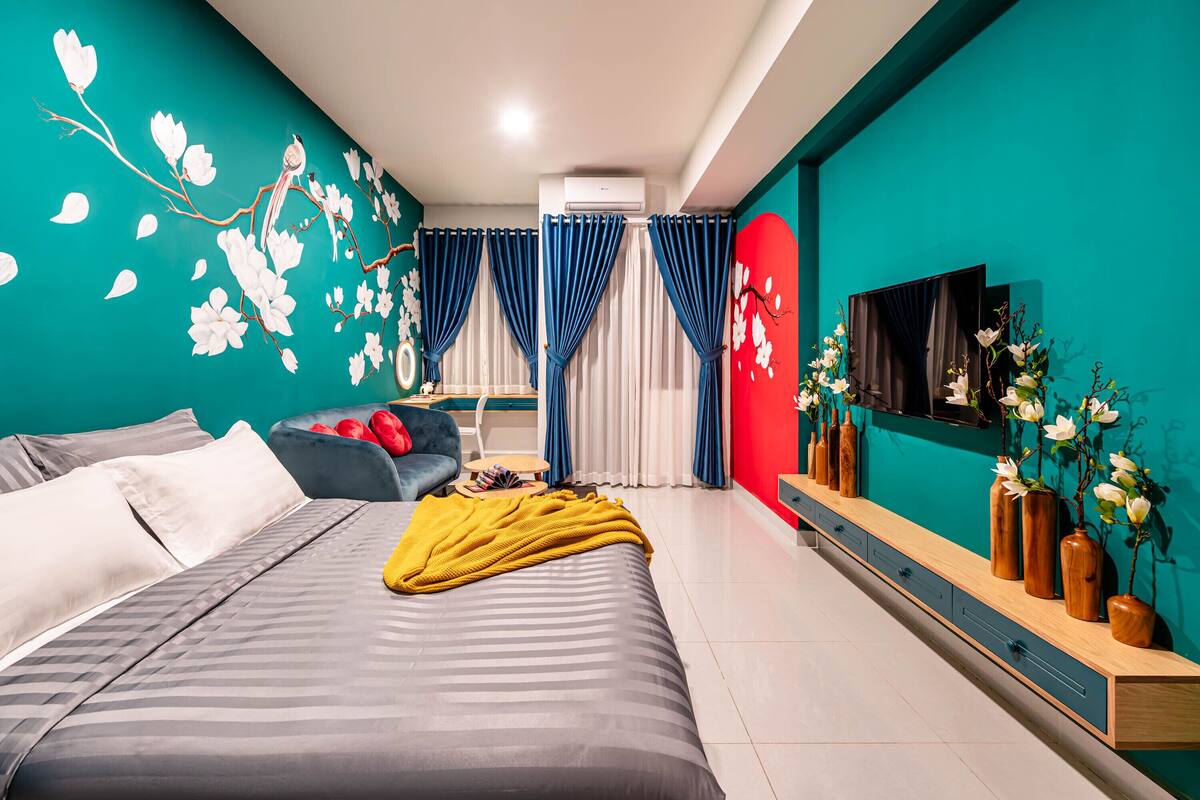 Un dormitorio moderno con cama, sofá, televisor y una pared decorada con flores.