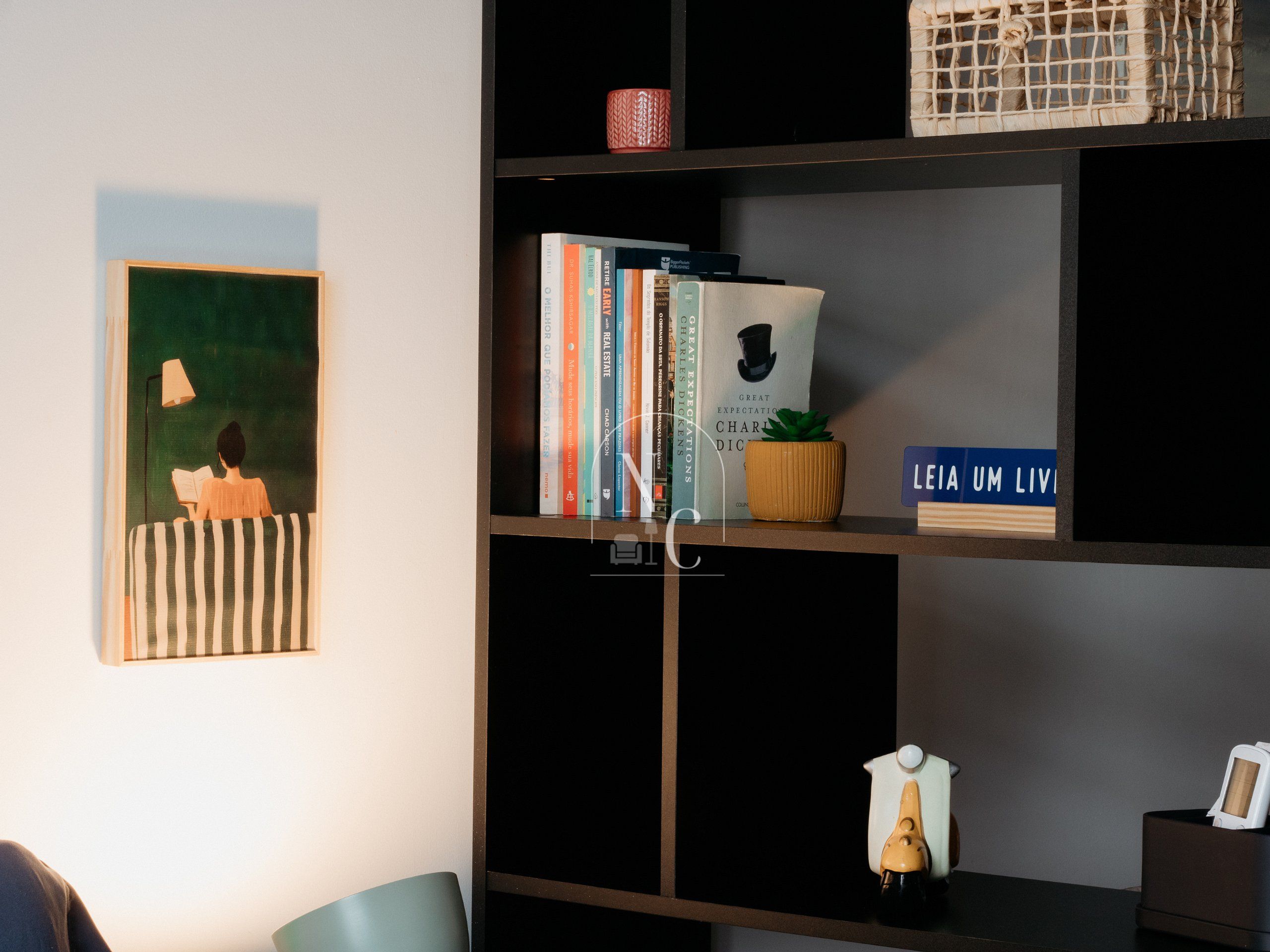 Una estantería con libros, una planta pequeña y un objeto decorativo.