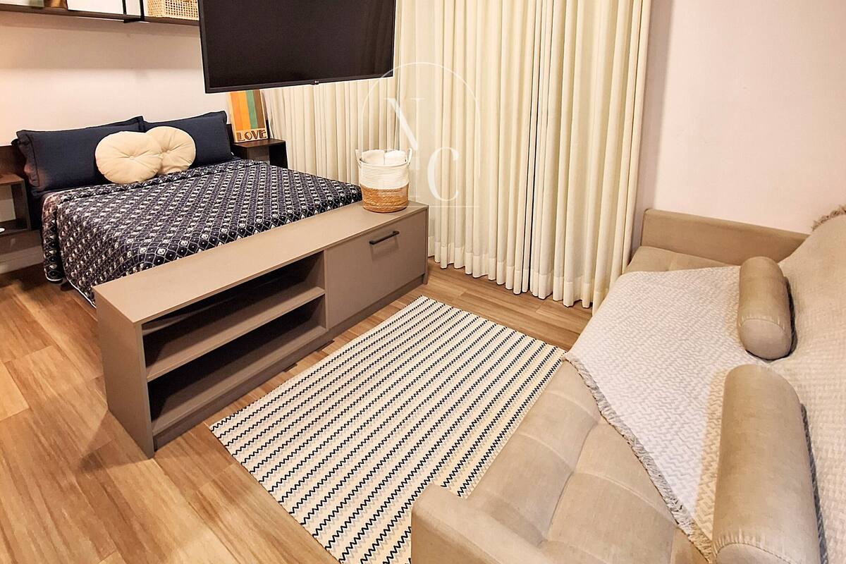 Quarto moderno com cama, televisão e sofá.
